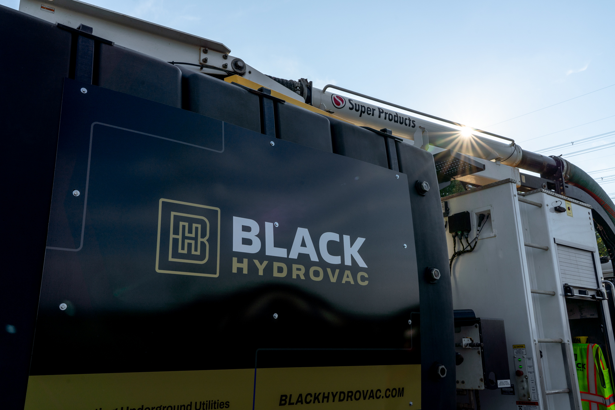 Black Hydrovac truck with logo parked in sunlight.