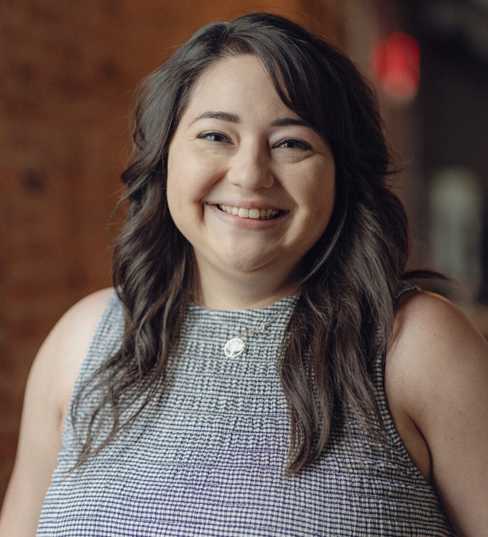 Woman with dark hair smiles indoors