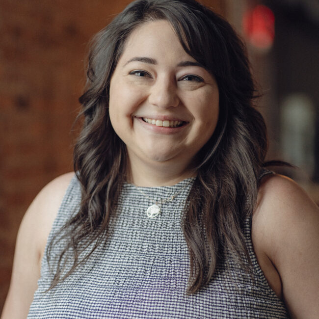 Woman with dark hair smiles indoors
