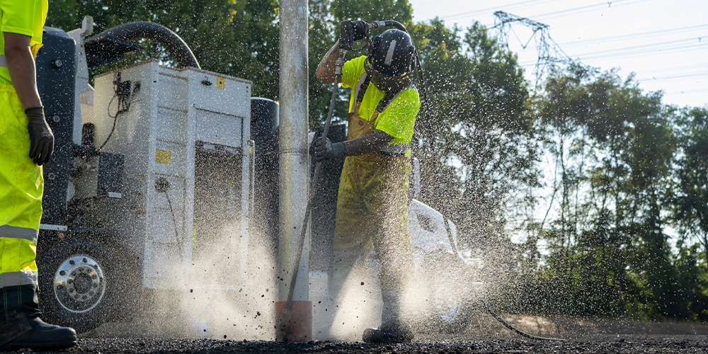 Worker sprays material at construction site amidst mist and debris.