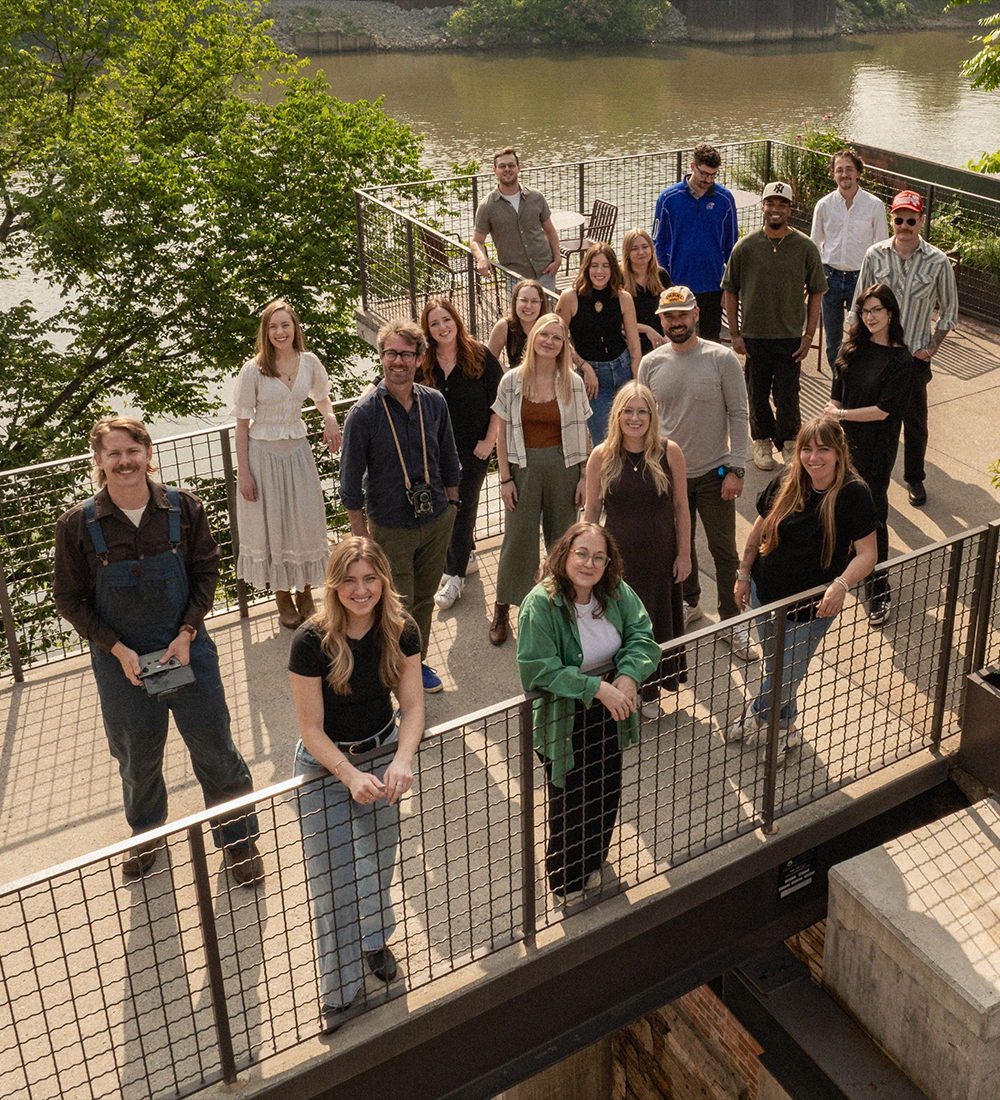 People pose on a metal walkway by a river.