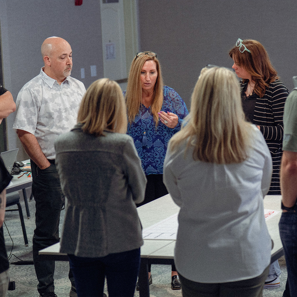 Adults discussing around a table with papers in a meeting.