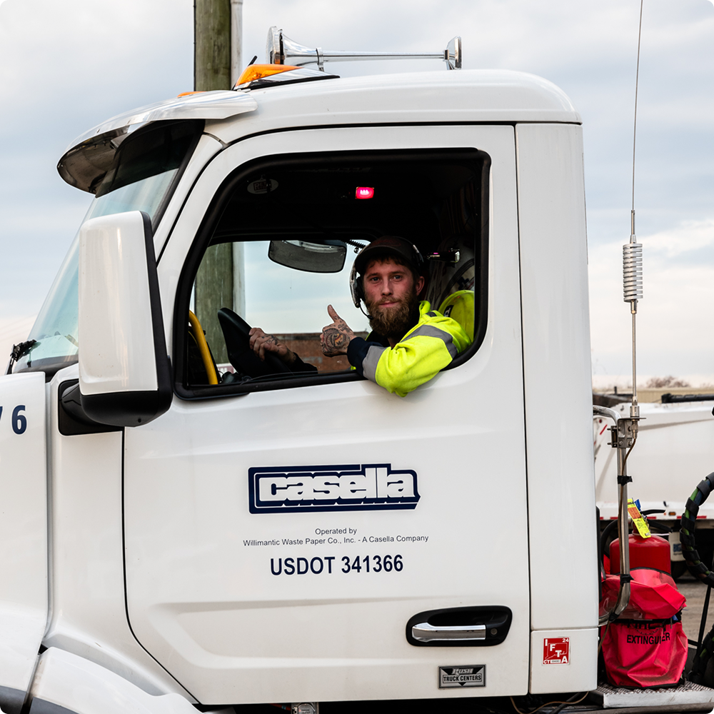 Man in Casella truck gives thumbs up out open window.