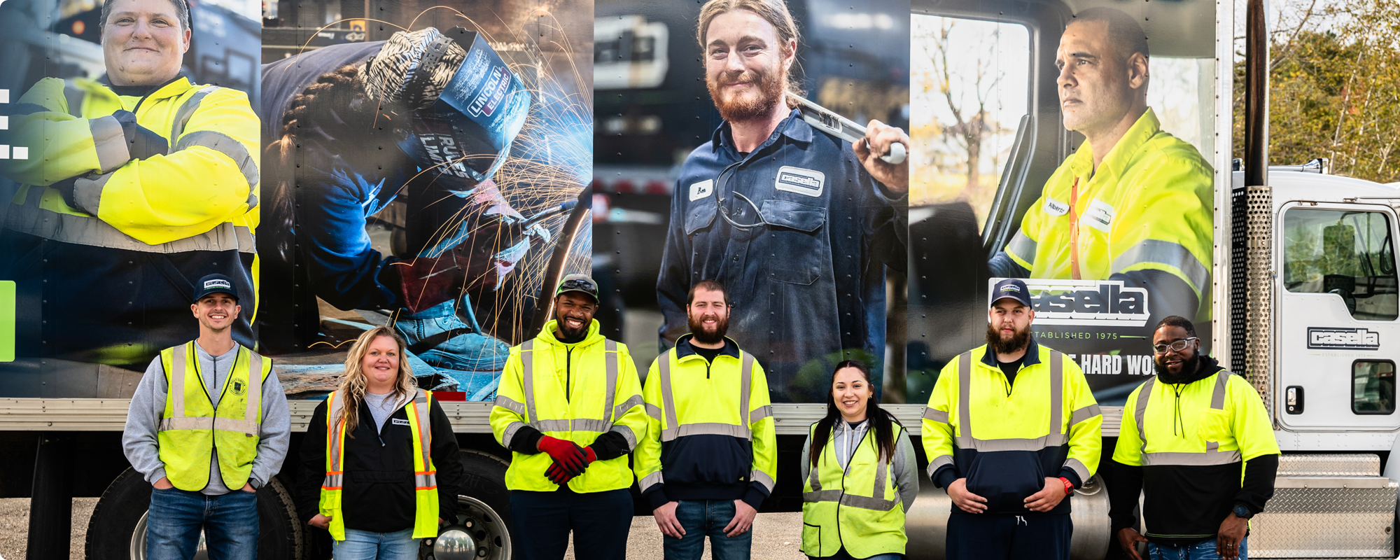 Seven workers in hi-vis gear stand by a truck with work uniform images.