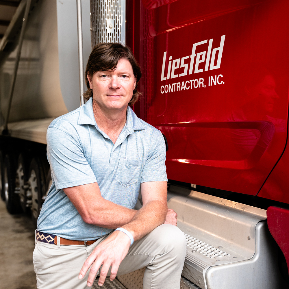 Man kneels by red Liesfeld Contractor, Inc. truck.