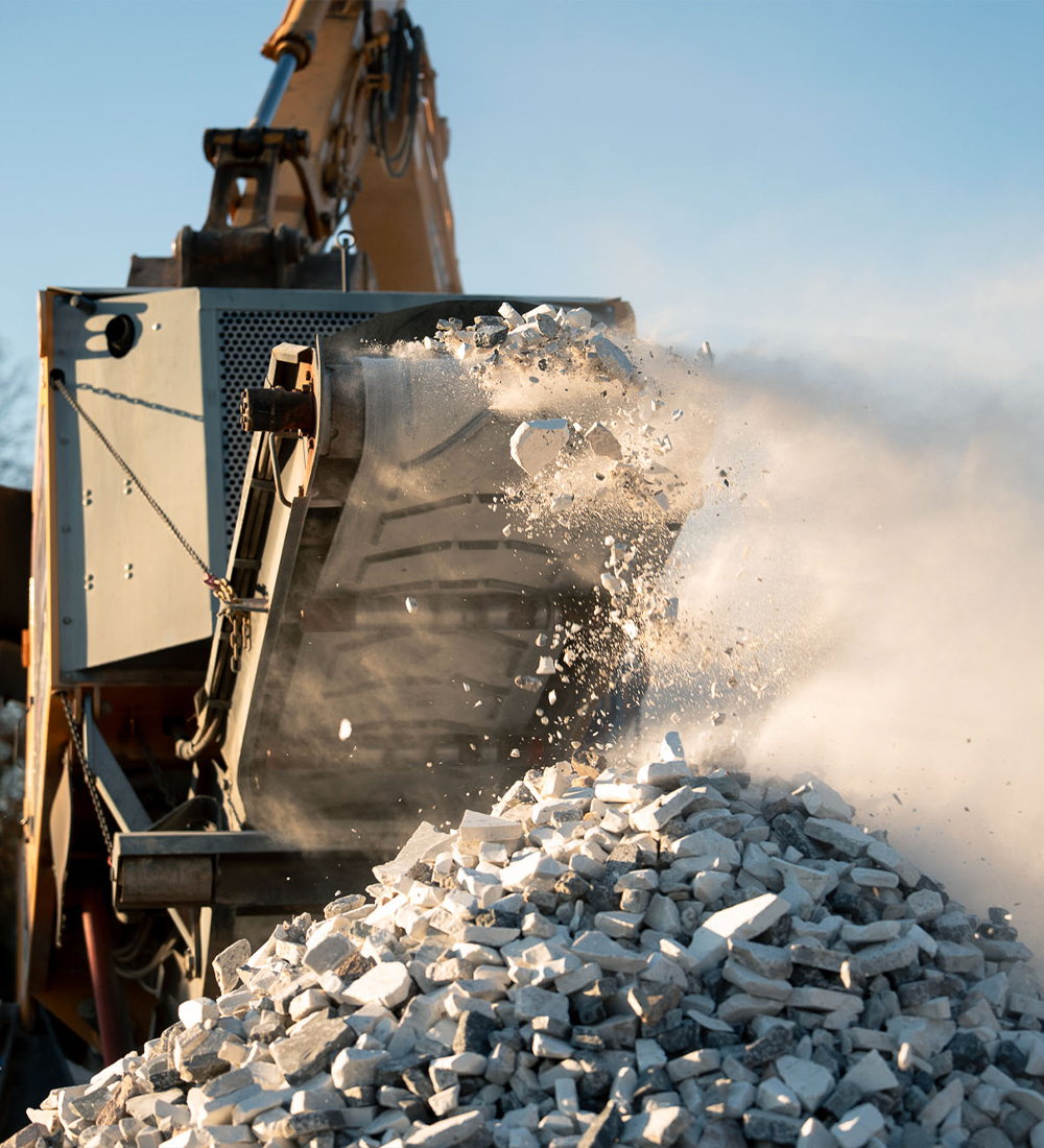 Rock crusher crushing stones, dust rising over broken rock pile.