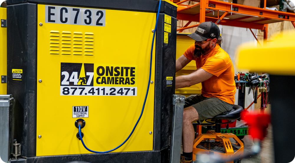 An employee in an orange t-shirt working on a 24/7 onsite security system.