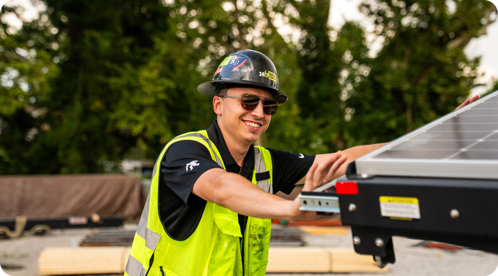 Employee at 24/7 Onsite Cameras in safety gear smiling.