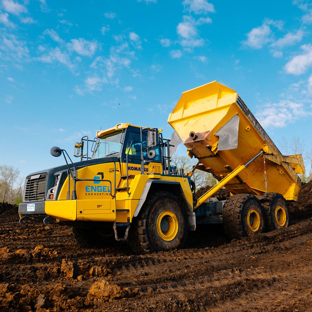 yellow dump truck unloading dirt