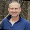 man smiling in a blue half-zip sweatshirt